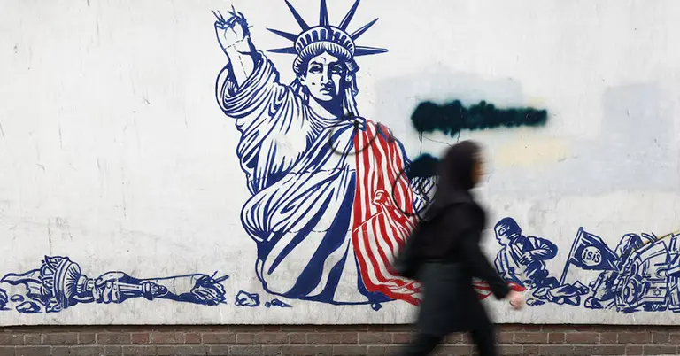 তেহরানের রাস্তায় যুক্তরাষ্ট্রবিরোধী দেয়ালচিত্রের পাশ দিয়ে হেঁটে যাচ্ছেন এক নারী